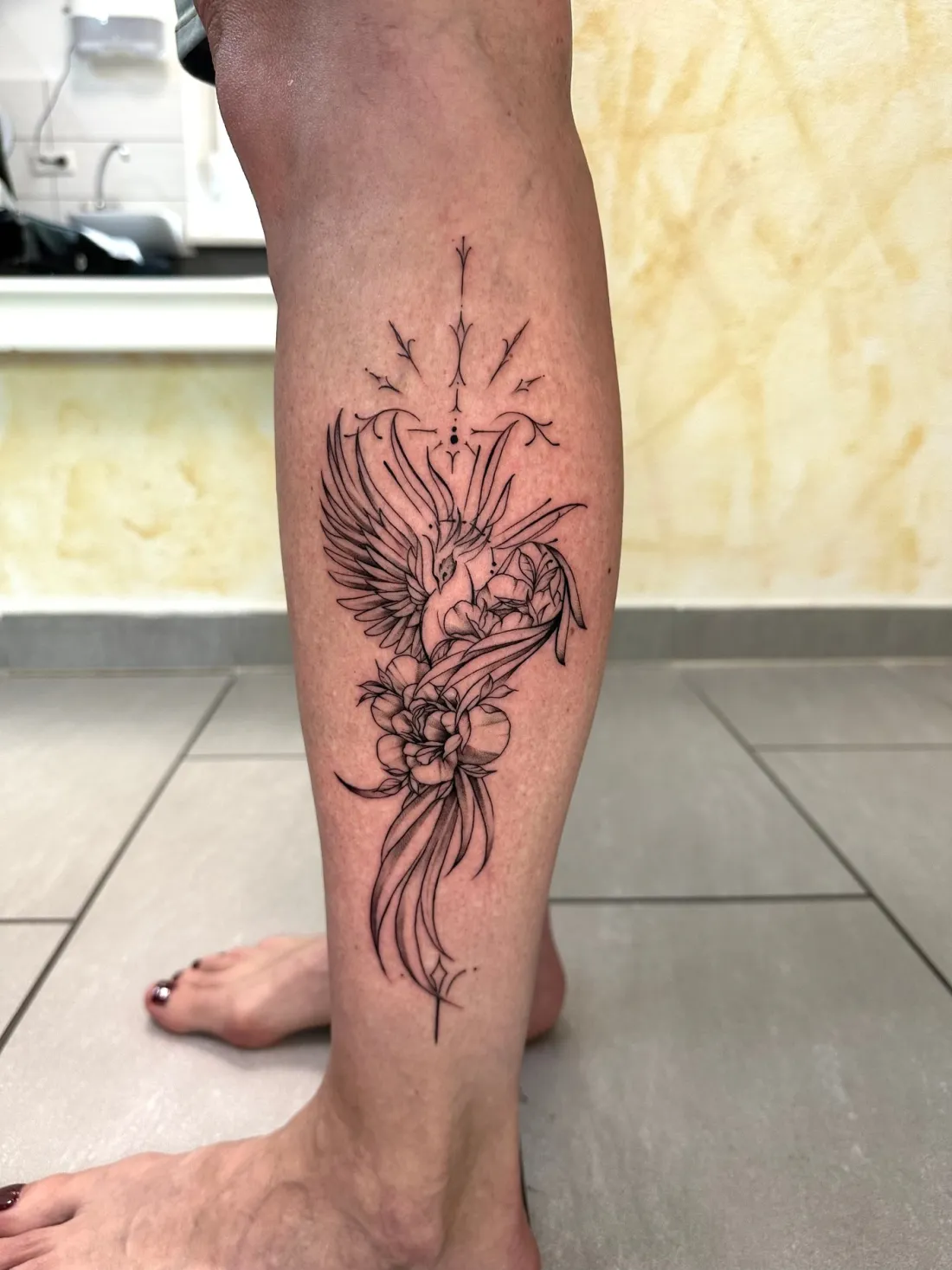 Phoenix mit Blueten auf Wade — Fine Line Tattoo von Marko